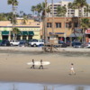 Surfers and jogger on Newport Beach, California