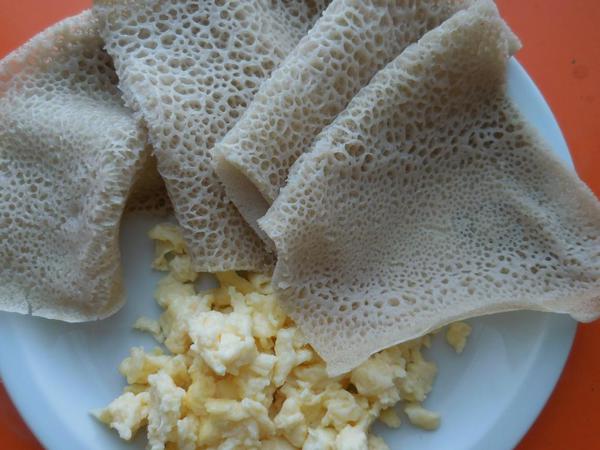 Injera with scrambled eggs. The injera is used to grasp the egg