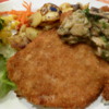 An extremely German meal of Schnitzel, fried potatoes, mushroom sauce and salad.